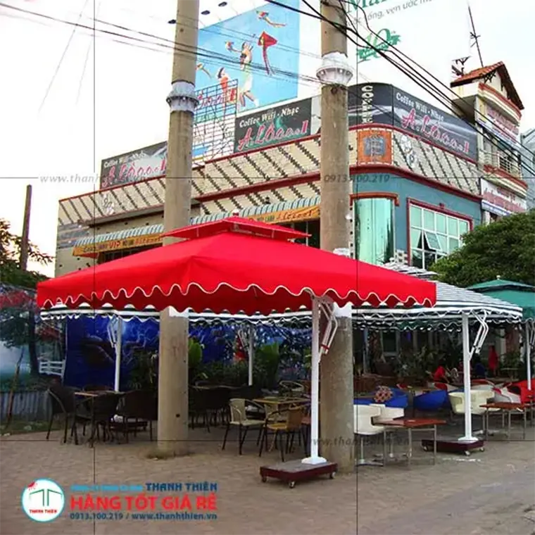 Ô dù lệch tâm 2 tầng màu đỏ đô che phủ bàn ghế mây tổng hợp tại sân vườn quán cafe ngoài trời