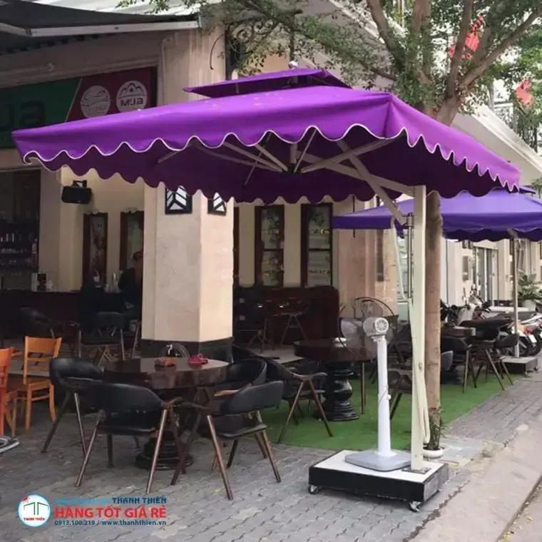 Ô dù vuông lệch tâm màu tím 2 tầng bèo diềm đặt trước quán cafe phố — bàn ghế gỗ và ghế da cafe