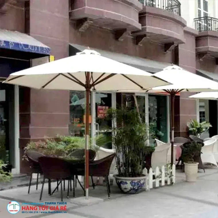 Ô dù chính tâm trắng kem trên cột gỗ đặt vỉa hè quán cafe — bố trí ngoài trời thương mại
